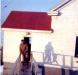 Lighthouse keeper and child dressed warmly outside Beacon Building in the Fall