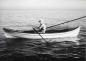 HUBERT EVANS ROWING HIS DOUBLE ENDER.  HIS HERRING RAKE RESTS ON A BRANCH YOKE. C. 1950'S