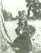 Little boy in traditional regalia wearing a head dress standing by a tree