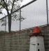 Outside wall and wire fence around three sides of the exercise yard.  It is topped by barbed wire.