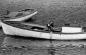 Boy bailing a trap boat tied to the fishplant wharf