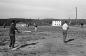 Young men play a pick-up softball game on a rocky field.