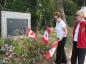 Beverley Beattie places flags in front of the original memorial in its new location