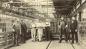 Men standing in munitons factory interior
