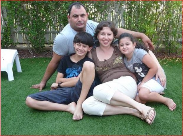 Informal portrait of family seated on the ground – parents and two children, one boy, one girl