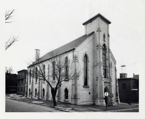 A brick building in the High Victorian Gothic style with arched windows and a central column once topped with a steeple.