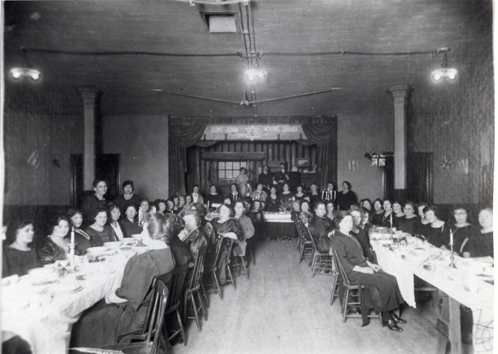 Women seated at long tables with one table as the head table in the background.