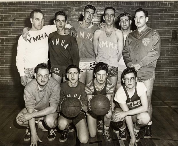 10 young men posing for team photograph – wearing long sleeved shirts with YMHA on the front.
