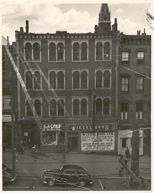 Four story building with 12 pairs of double windows on three upper floors – signage at street level for “Jack Calp The Men’s Shop and “Wiezel Bros.”