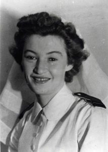 Portrait officiel d’une jeune femme portant le voile blanc et l’uniforme blanc des infirmières militaires.