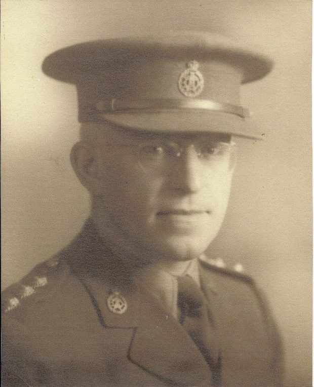 Formal portrait of man with wire framed glasses and wearing uniform of Canadian Army with pin for Canadian Dental Corps