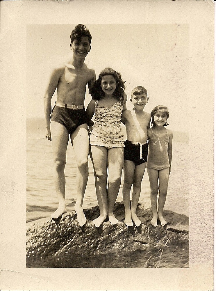 Four children in bathing suits standing on a rock – arranged from left from tallest and oldest to youngest and shortest
