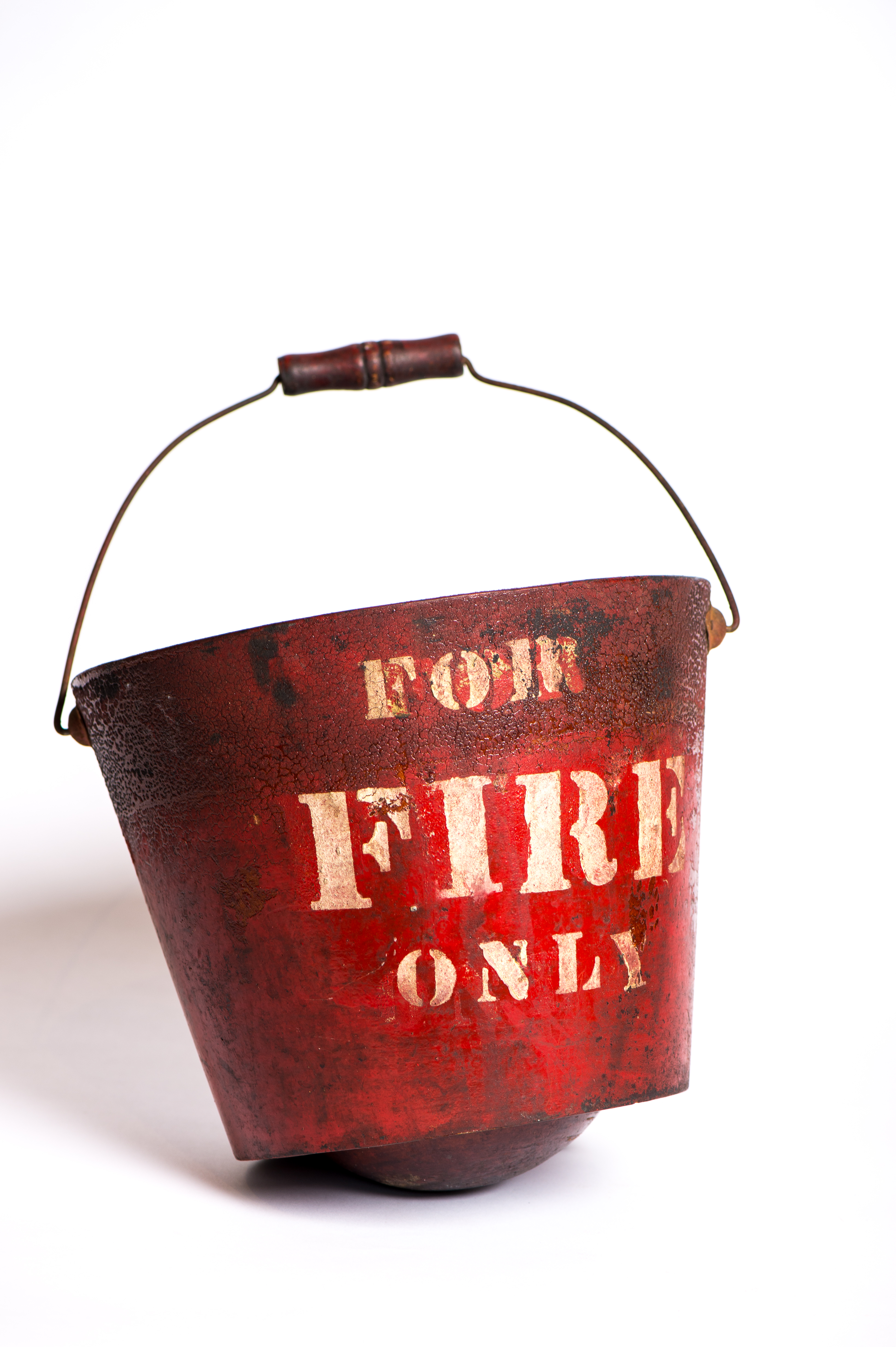 Photograph of a red round-bottomed fire bucket bearing the English words ‘For fire only’ in block letters.