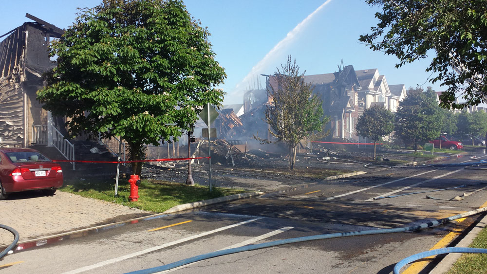 Photograph showing a street that has been completely devastated and blackened by fire. Where homes once stood there is nothing but rubble.