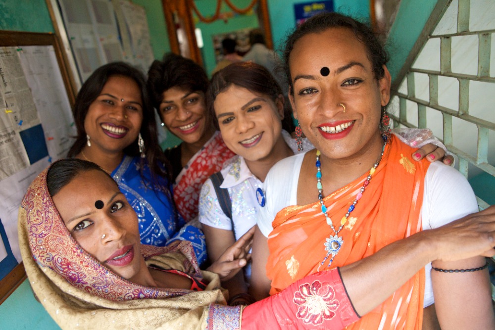 Group of five people huddled together, smiling at the camera.