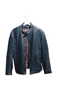 A dark blue leather jacket on a white hanger. The jacket is slightly open, revealing a colourful pattern underneath.