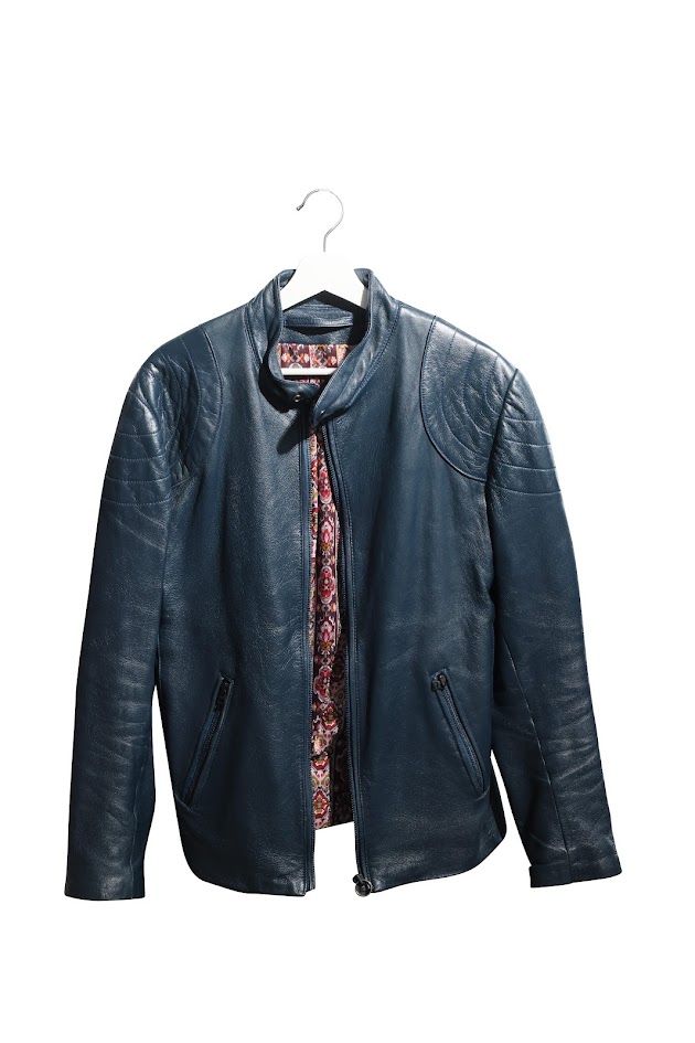 A dark blue leather jacket on a white hanger. The jacket is slightly open, revealing a colourful pattern underneath.