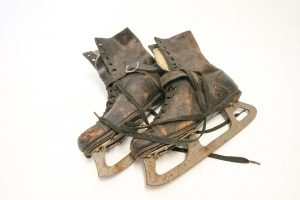 Paire de patins, chaussures en cuir brun foncé avec lanière devant la cheville, doublure moletonnée,  lames rouillées.