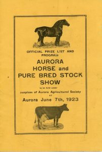 The front cover of a small rectangular program consisting of black lettering printed on a gold background with engraved illustrations of a horse and a cow all enclosed within a printed rectangular border