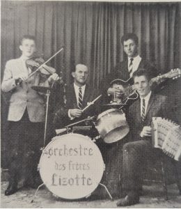 Black and white photograph of the Orchestre des Frères Lizotte. From left to right, all wearing jackets and ties: Jean-Paul Lizotte, Jean-Léon Pelletier, Maurice Lizotte and Réjean Lizotte. Some band members are sitting and others are standing in front of a curtain.