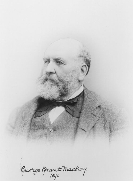 Black and white portrait of an older bearded man, dressed in a suit with a big bow tie.