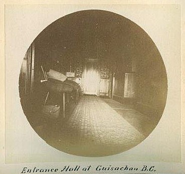 Black and white round photo of a hallway, several chairs, and a carpet runner.