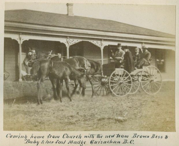 Black and white photo of a horse and wagon with four people in front of a house.