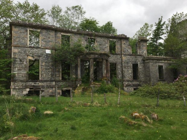 Colour photo of the remaining front wall of the ruins of a stone building.