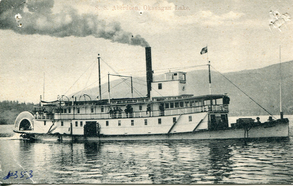 Black and white postcard of a large paddlewheeler with two decks and smoke billowing from the stack.