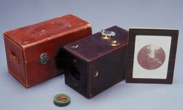 First Kodak box camera, with a case, and a framed photo