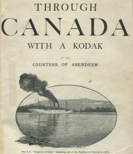 Book cover of Lady Aberdeen's 1893 book, Through Canada with a Kodak, with an oval photo of a ship sailing out of the Vancouver harbour