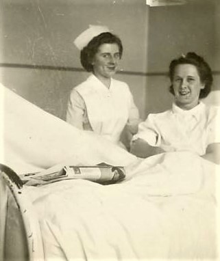 Photograph of Cecile Turcotte sitting up on a bed smiling with a nurse at her side at the Ottawa Civic Hospital after the Almonte Train Wreck, 1943