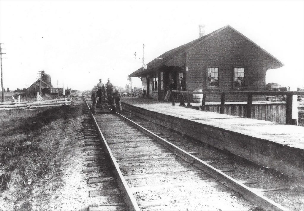 Historic photograph of the Ashton train station with four men on the track, 1940s