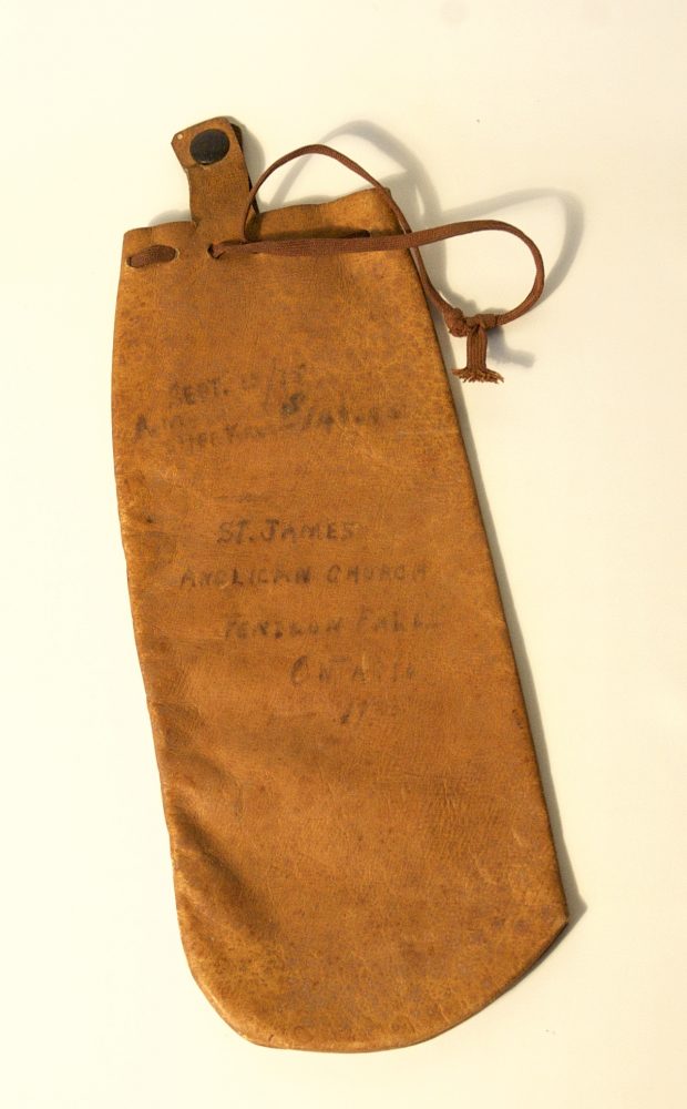 Small leather pouch with drawstrings and hand written text on the material.