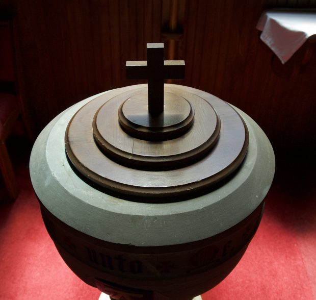 The cover of the font is a wooden oak circular cover with a cross standing on it that is approximately 15 cm high.