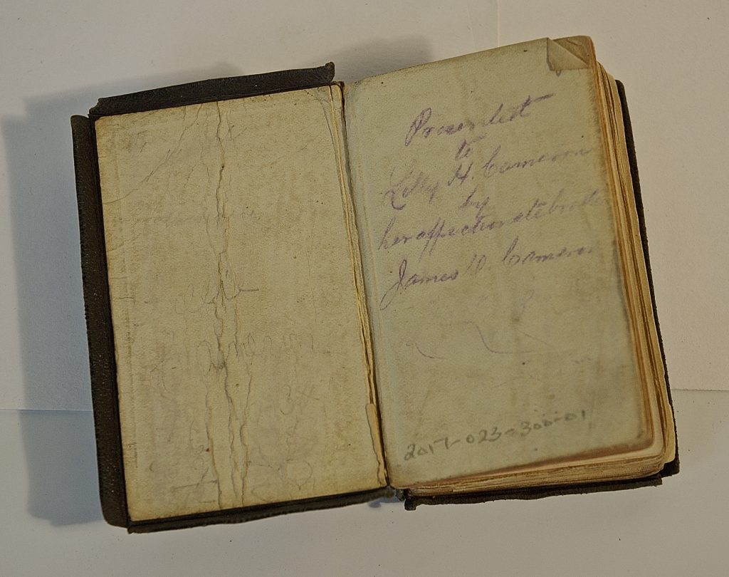 A small bible shows the delicate condition of the small children's bible. The purple ink inscription reads "Presented to Lilly H. Cameron by her affectionate brother James D. Cameron"