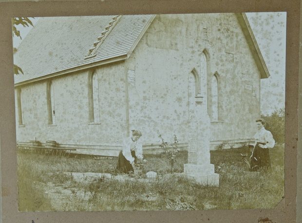 Black and white photograph of two women at back of St. James tending to a grave circa 1880.