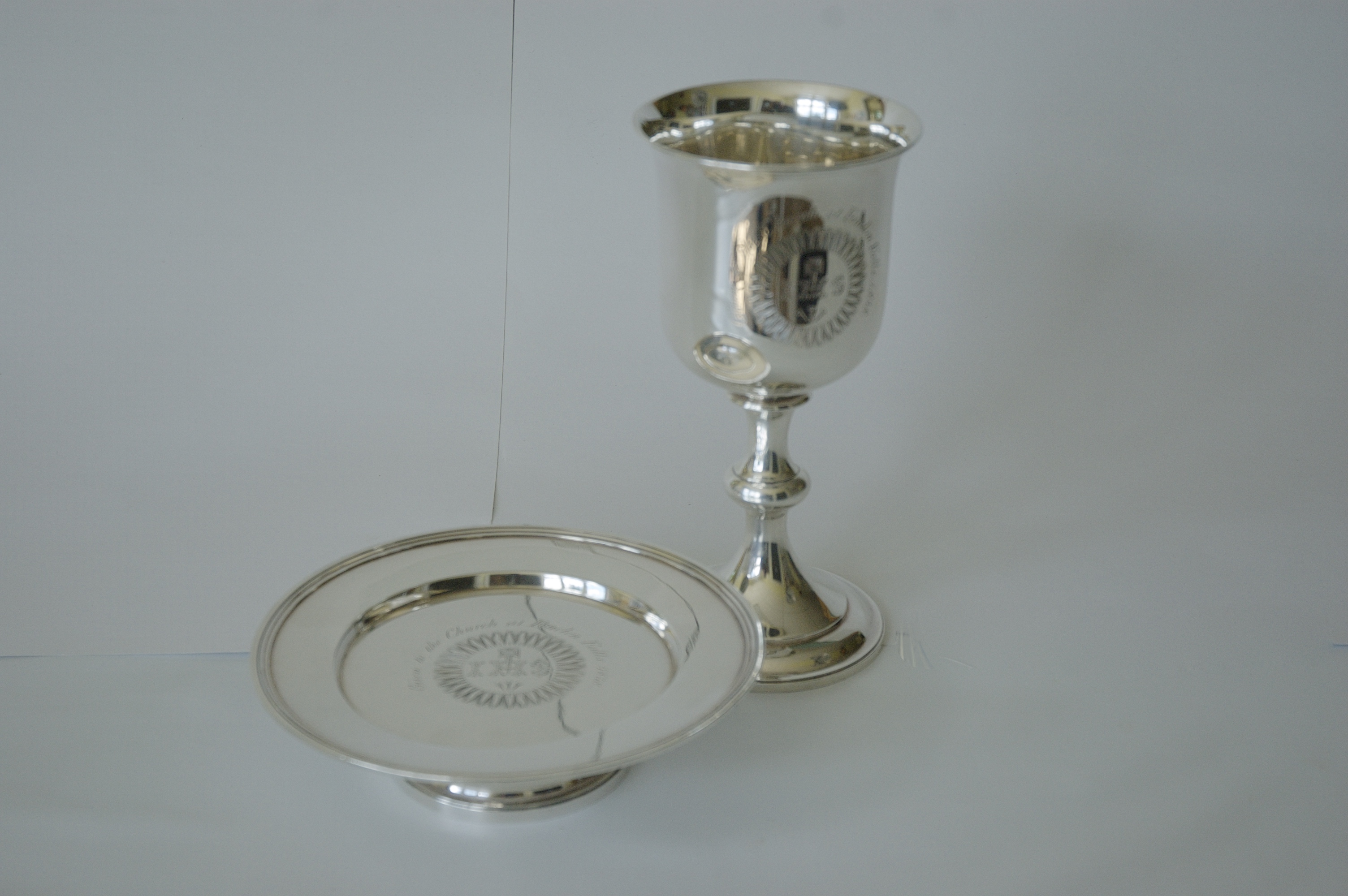 Silver communion plate used to serve bread; and silver chalice used to serve communion wine.