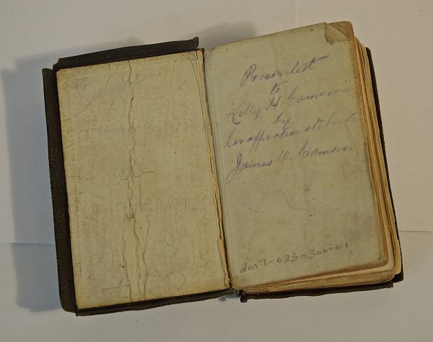 A small bible shows the delicate condition of the small children's bible. The purple ink inscription reads Presented to Lilly H. Cameron by her affectionate brother James D. Cameron