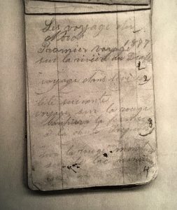 Photograph of a page from a notebook. Handwritten in pencil are the words “Les voyages du Nord. 1877, Premier voyage sur la rivière du Diable” (“Travels Northward. 1877, first trip on the Diable River”). A number of other destinations follow.