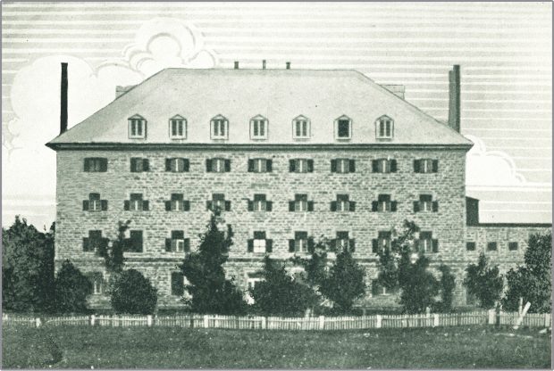 Drawing of a four-storey stone building with a hipped roof. Nine latticed windows are visible per floor, while the roof features seven dormers. Chimneys adorn each end of the roof. To the rear, at right, is a two-storey stone building. The property is ringed by a wooden fence.