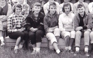 Segment d’une photo en noir et blanc montrant cinq jeunes femmes assises dehors sur des caisses de bois.