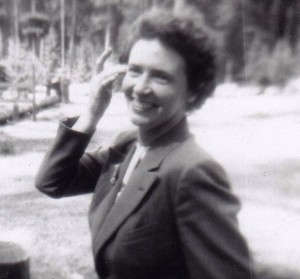 Black and white candid headshot photo of a woman smiling and walking by.