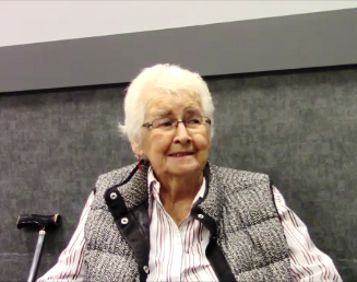 Colour photo of a senior woman with short white hair and glasses.