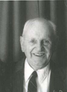 Black and white photo of Bill Parsons smiling, wearing a suit.