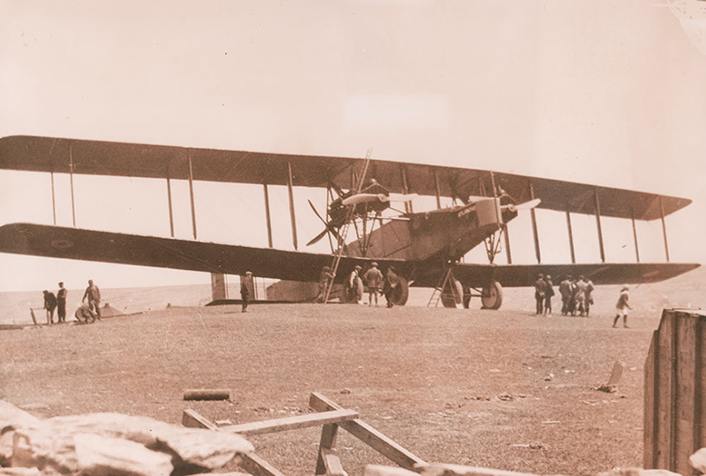 A black and white photograph of the Handley Page Atlantic. The size of the aircraft is astounding, as approximately 12 individuals stood around the plane, are the same height of the plane's wheels, just reaching the bottom of its lower wing.