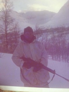 Al Murphy, wearing a white parka, stands in the snow holding his rifle while on military exercises in Norway in the late 60s