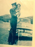 Pat Gaulton in uniform holds a child in his arms