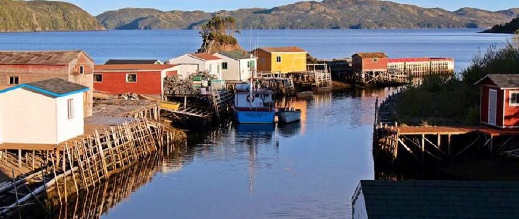 colourful sheds line a wharf on a rocky bay