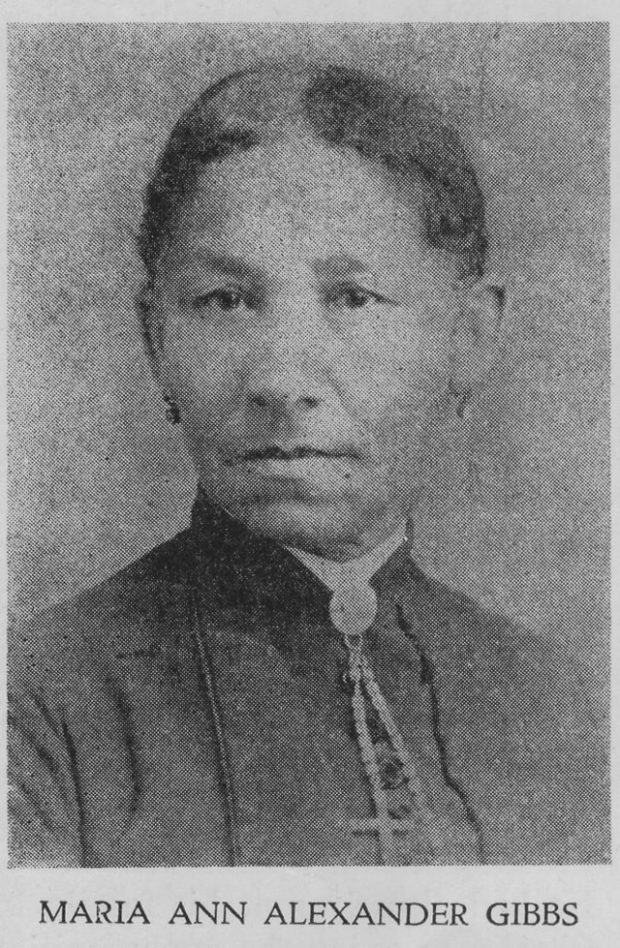 black and white professional portrait, turned to face the camera, hair pulled back, wearing muted colored dress with high collar, broach with necklace